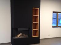 Kamin mit schwarzer Verkleidung und integriertem Holzregal 