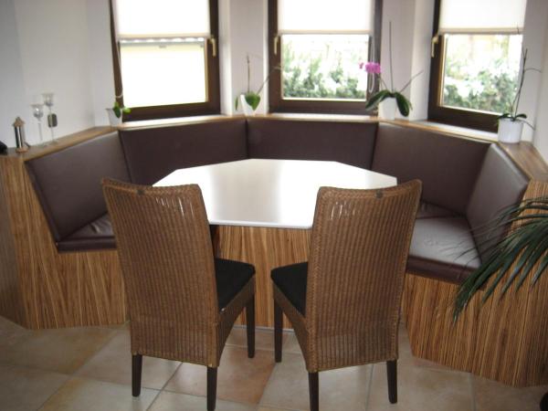 Holztisch mit weißer Tischplatte und Eckbank mit braunem Polster