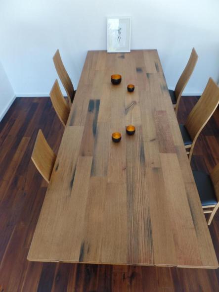 Holztisch mit Maserung und Holzstühle mit schwarzen Polstern 